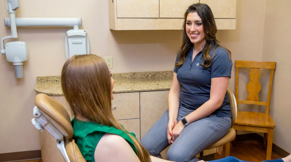 Dental team member talking with a patient in the treatment chair
